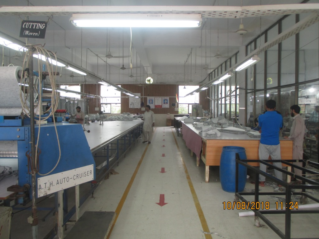 Pensy’s cutting room in Lahore, with long cutting tables and a marked central aisle, photographed in 2018